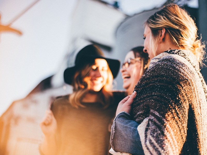 Exemplarische Abbildung von drei Frauen die lachen im Sonnenuntergang