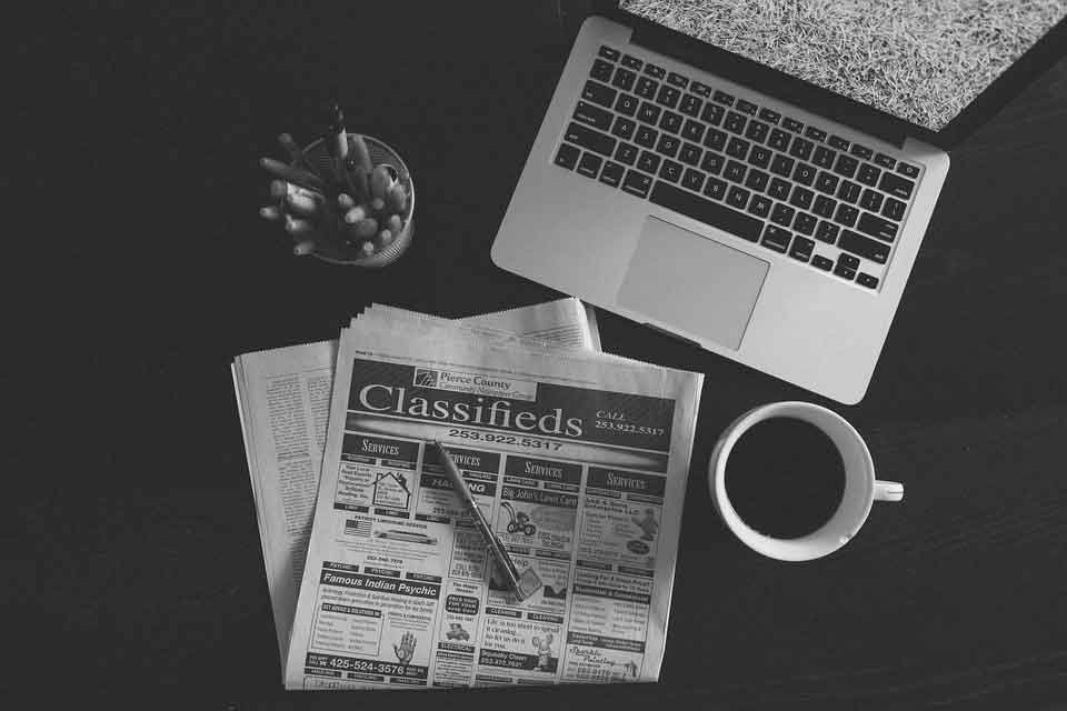 Schwarz Weiß Abbildung eines Laptops einer Zeitung und einer Tasse Kaffee