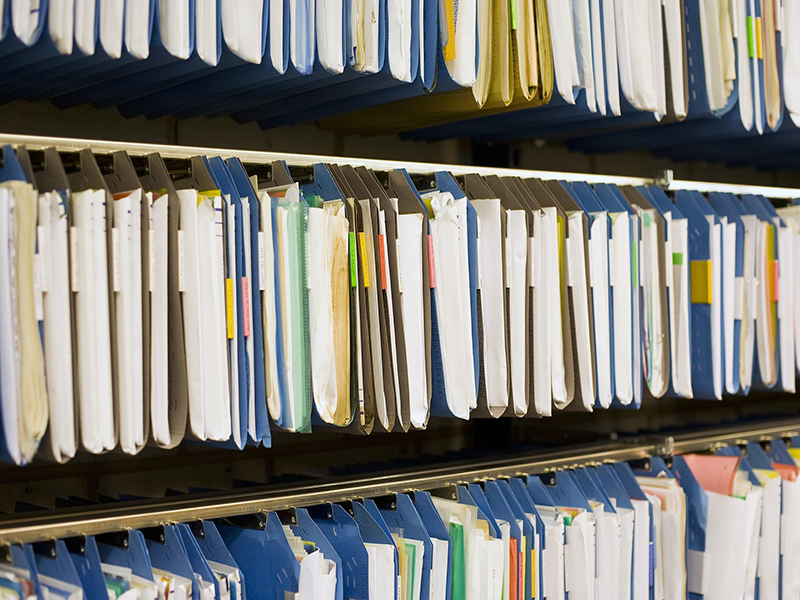 Archivierte Dokumente in Heftmappen in einem Regal, die sortiert aufgehängt wurden